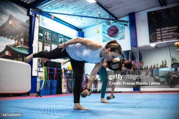 mature woman training using a dumbbell at gym - op een been staan stockfoto's en -beelden