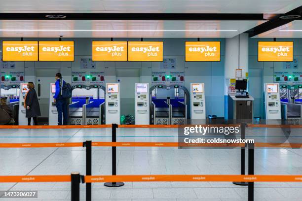 people using easyjet self-service check-in terminals in the airport - easyjet stock pictures, royalty-free photos & images