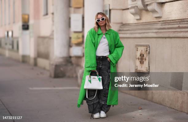 Karin Teigl seen wearing Celine white oval Triomphe sunglasses, gold jewelry, NA-KD green leather long coat, Loewe white logo tanktop, Hermès white...