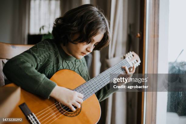 young boy playing guitar - country rock music stock pictures, royalty-free photos & images