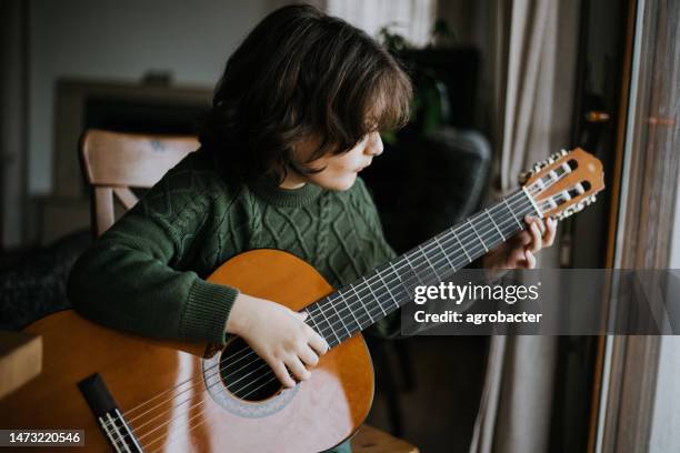 young boy playing guitar - country rock music stock pictures, royalty-free photos & images