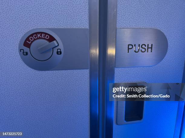 Door lock on interior door of airplane restroom on Airbus aircraft, with blue lighting, In flight, March 9, 2023.