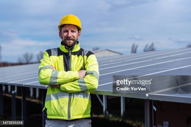 a happy confident electrical worker standing on solar power station - handyman smiling imagens e fotografias de stock