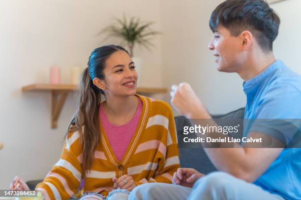 young couple looking each other in the eyes sitting in the living room at home - casa calvet stock pictures, royalty-free photos & images