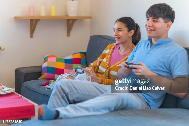 young couple sitting on a couch in a living room and playing video games - casa calvet stock pictures, royalty-free photos & images