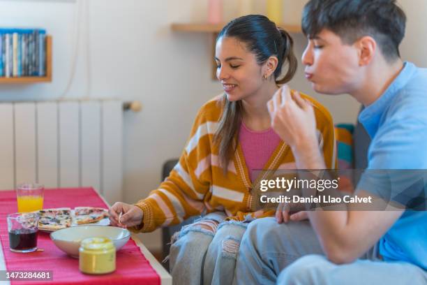 young couple eating pizza and nacho chips together at home - casa calvet stock pictures, royalty-free photos & images