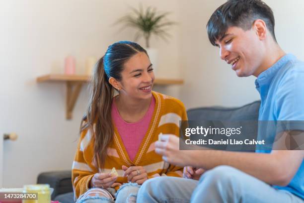 young couple smiling happily while eating nachos with guacamole at home - casa calvet stock pictures, royalty-free photos & images