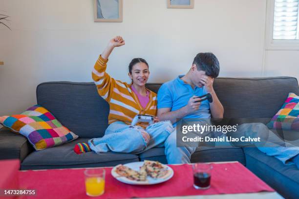 man and woman, young heterosexual couple on sofa playing video games. - casa calvet stock pictures, royalty-free photos & images