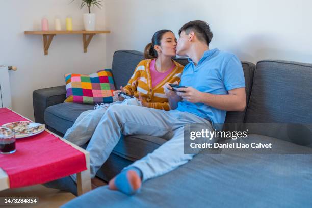 young couple kissing while playing video games - casa calvet stock pictures, royalty-free photos & images