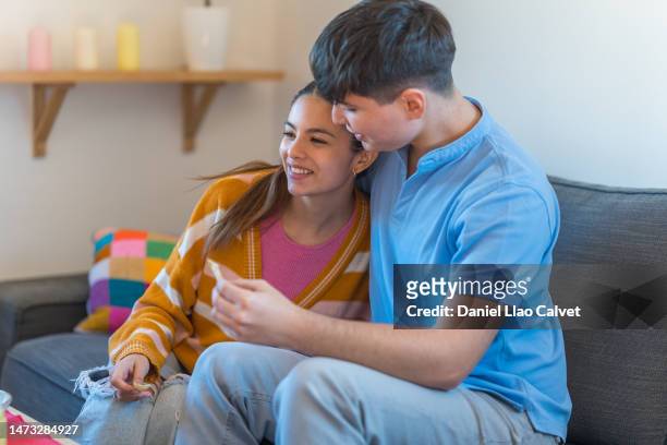 young couple happily embrace each other sitting in the living room at home - casa calvet stock pictures, royalty-free photos & images