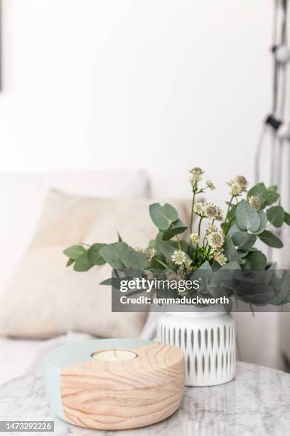 close-up of a vase of flowers and candle on a table in a living room - side table stock pictures, royalty-free photos & images