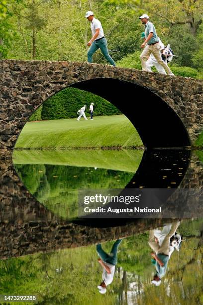 Marc Leishman of Australia, Victor Perez of France, and Jason Kokrak walk across the the Hogan Bridge to No. 12 in Amen Corner during Round 2 of the...