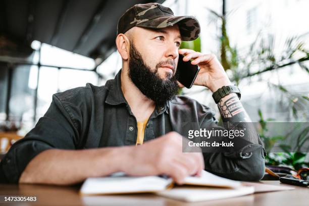 morning coffee before work. casual man in cafe using phone and note pad - café da internet stock pictures, royalty-free photos & images