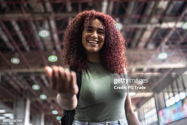 porträt einer jungen frau, die am flughafen winkt - heranlocken stock-fotos und bilder