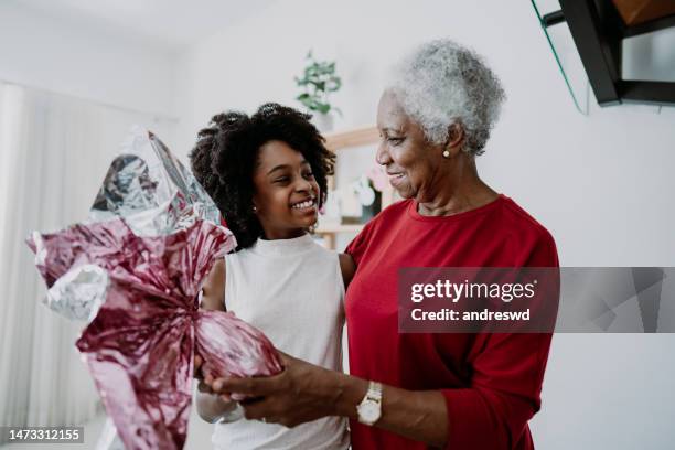 grandmother giving granddaughter an easter egg - african easter stock pictures, royalty-free photos & images