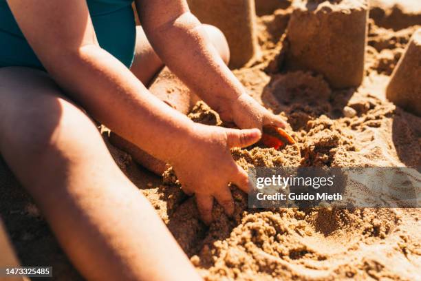 toddler girl playing with a bucket in the sand of a beach. - kind sandburg stock-fotos und bilder