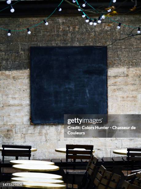 close-up of a restaurant terrace with tables, chair and empty blackboard on a weathered wall in brussels, belgium - pub wall stock pictures, royalty-free photos & images