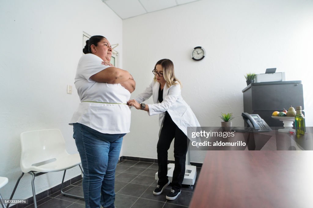 Nutricionista usa cinta métrica alrededor de una mujer con sobrepeso