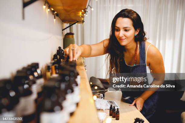 brazilian woman perfumer working in her workshop, choosing essential oils - aromatherapy stock pictures, royalty-free photos & images