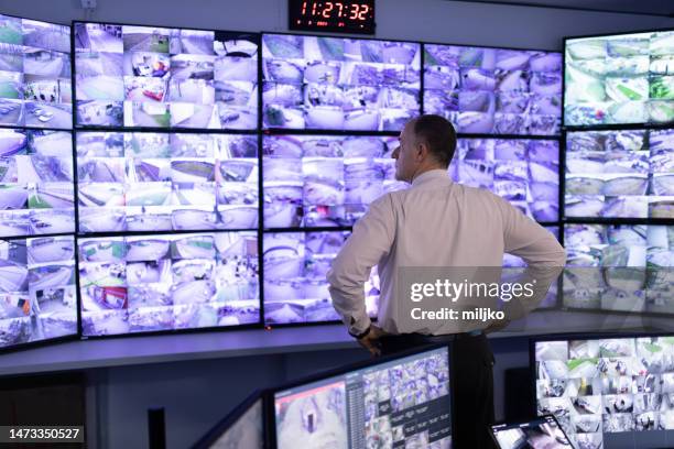 man working in surveillance room and looking at camera - control room monitors stockfoto's en -beelden