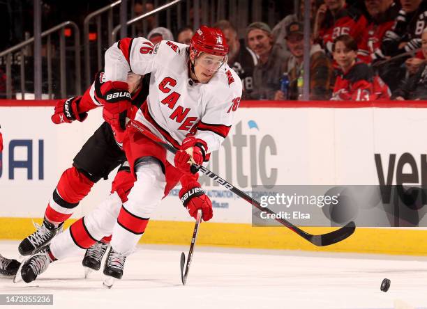 Brady Skjei of the Carolina Hurricanes takes the puck as Michael McLeod of the New Jersey Devils defends during the third period at Prudential Center...