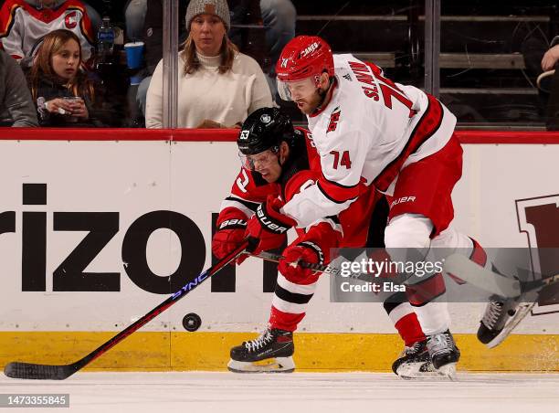 Jesper Bratt of the New Jersey Devils and Jaccob Slavin of the Carolina Hurricanes fight for the puck during the third period at Prudential Center on...