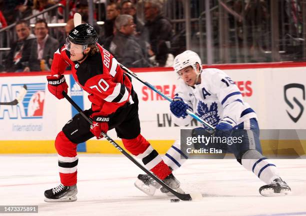 Jesper Boqvist of the New Jersey Devils takes the puck as Mitchell Marner of the Toronto Maple Leafs defends during the first period at Prudential...