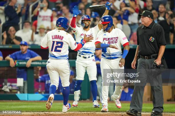 Francisco Lindor of Puerto Rico is congratulated by Martin Maldonado after scoring on a double hit by Enrique Hernandez in the second inning against...