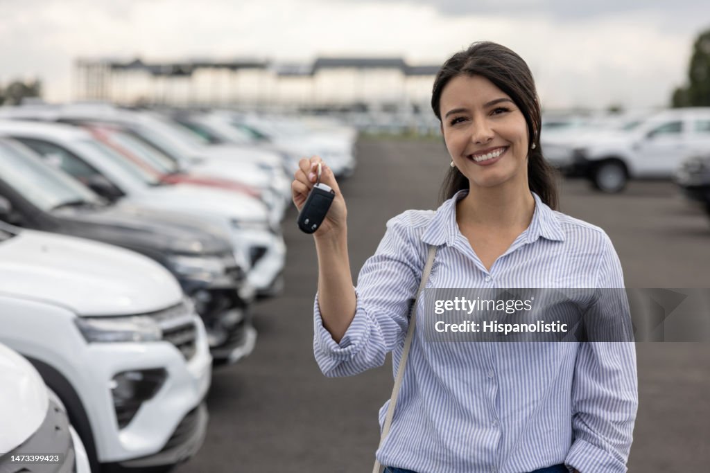 Happy woman at the dealership holding the car keys