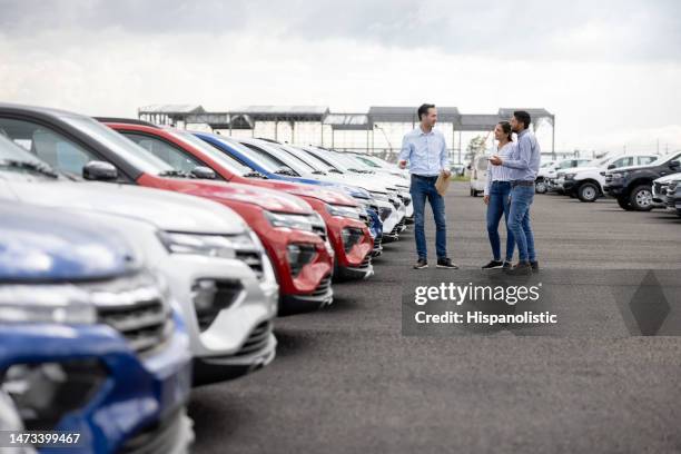 venditore che mostra le auto a una coppia presso la concessionaria - venditore di automobili foto e immagini stock