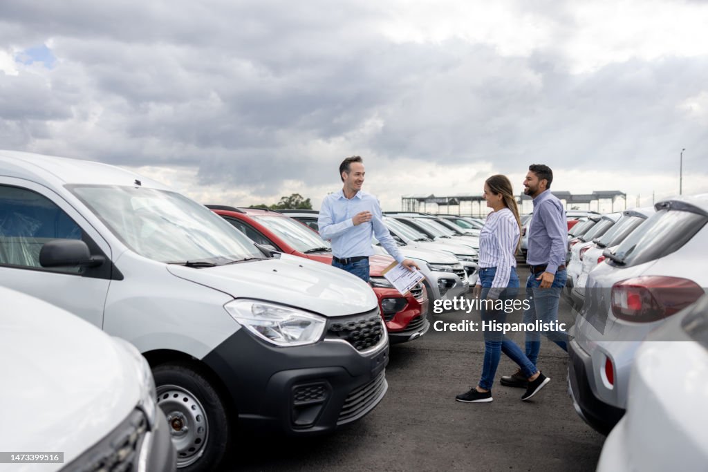 Salesman showing cars to a couple at the dealership