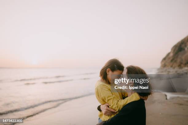 mother and young daughter embracing on beach at sunset - mom and young daughter ストックフォトと画像