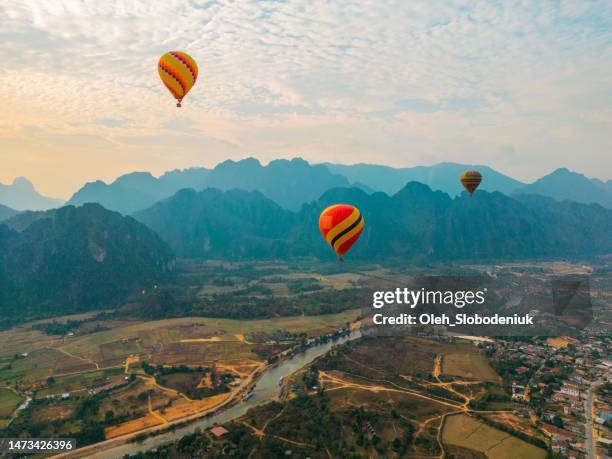 aerial view of red hot air balloon above the valley - vang vieng balloon stock pictures, royalty-free photos & images