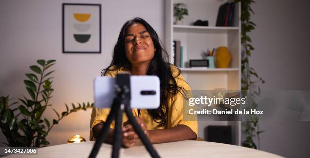 young indian woman recording video talking to followers during live stream on social media. female content creator using phone to communicate with subscribers making funny face. - content creation stock pictures, royalty-free photos & images