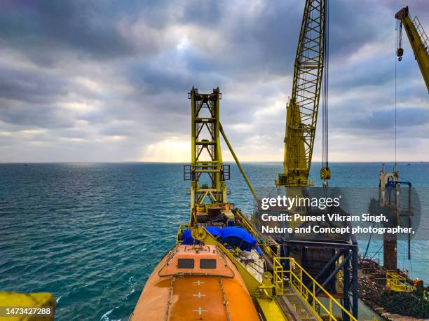 offshore construction cranes in the backdrop of sunset - hydrocarbon stock pictures, royalty-free photos & images