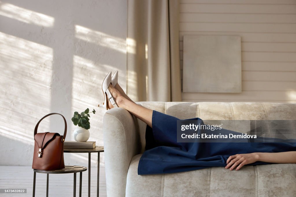 Crop woman in elegant dress relaxing on couch