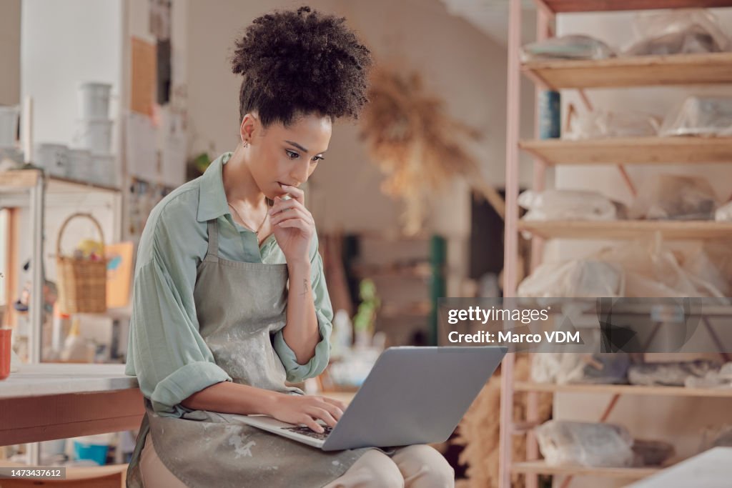 Black woman artist, thinking and laptop in studio for inspiration, goal or online store management. Potter, sculptor and computer for ideas, design or retail website for sales on internet in workshop