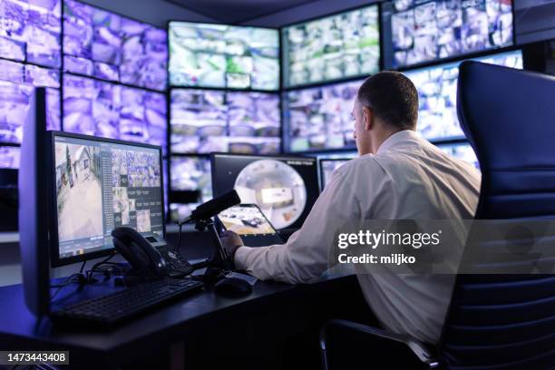 man working in surveillance room and looking at monitors - control room monitors stockfoto's en -beelden