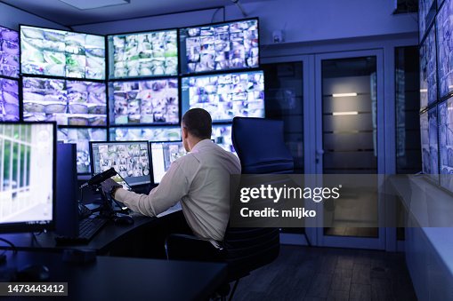 Hombre trabajando en sala de vigilancia y mirando monitores Hombre trabajando en sala de vigilancia y mirando monitores
