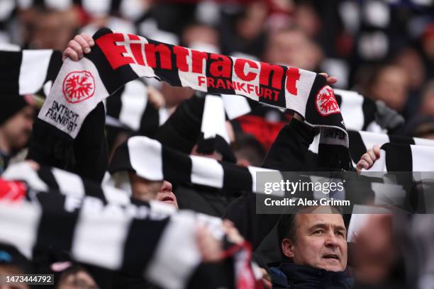 Fans of Eintracht Frankfurt hold up their scarves as they cheer for their team during the Bundesliga match between Eintracht Frankfurt and VfB...