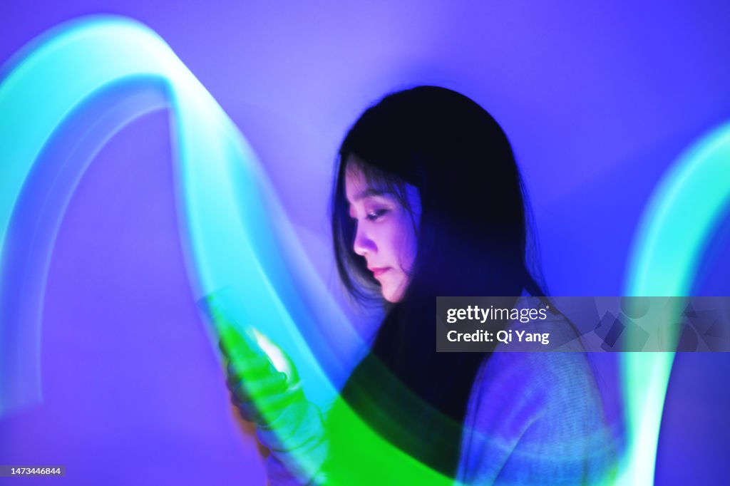 Young Asian woman using a smartphone on the holographic background. Concept Technology