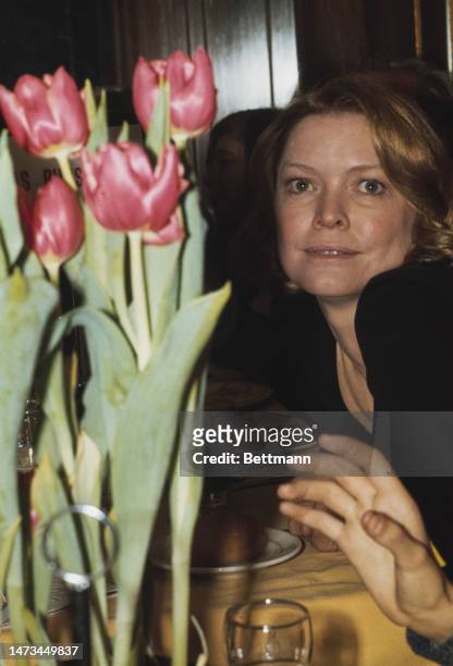 Close-up of actress Ellen Burstyn sitting near a pot of tulips at a party in New York on March 13th, 1975.