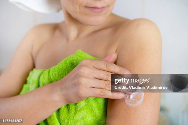 unknown woman applying progesterone cream onto her arm - oestrogen stock pictures, royalty-free photos & images