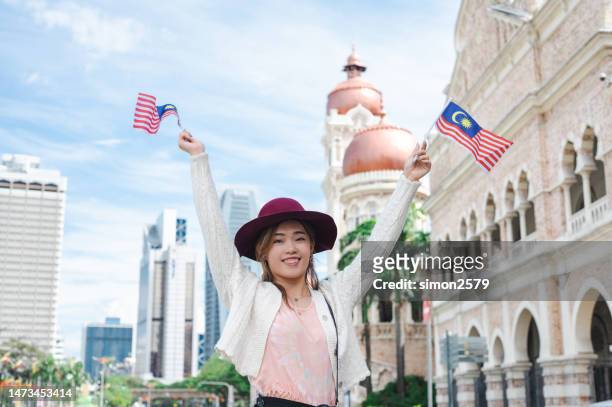a young malaysian chinese woman proudly display her patriotic spirit and solidarity in celebrating the national day at merdeka square, kuala lumpur malaysia. - malaysia kuala lumpur merdeka square stock pictures, royalty-free photos & images