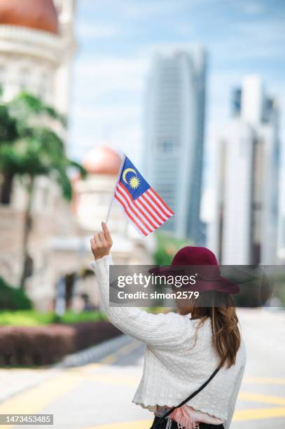 a young female tourist proudly displays the malaysian flag at merdeka square in kuala lumpur, malaysia - malaysia flag stock pictures, royalty-free photos & images