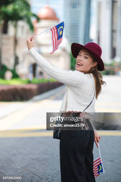 merdeka square comes alive with national fervor as a young female tourist proudly displays the malaysian flag - malaysia kuala lumpur merdeka square stock pictures, royalty-free photos & images