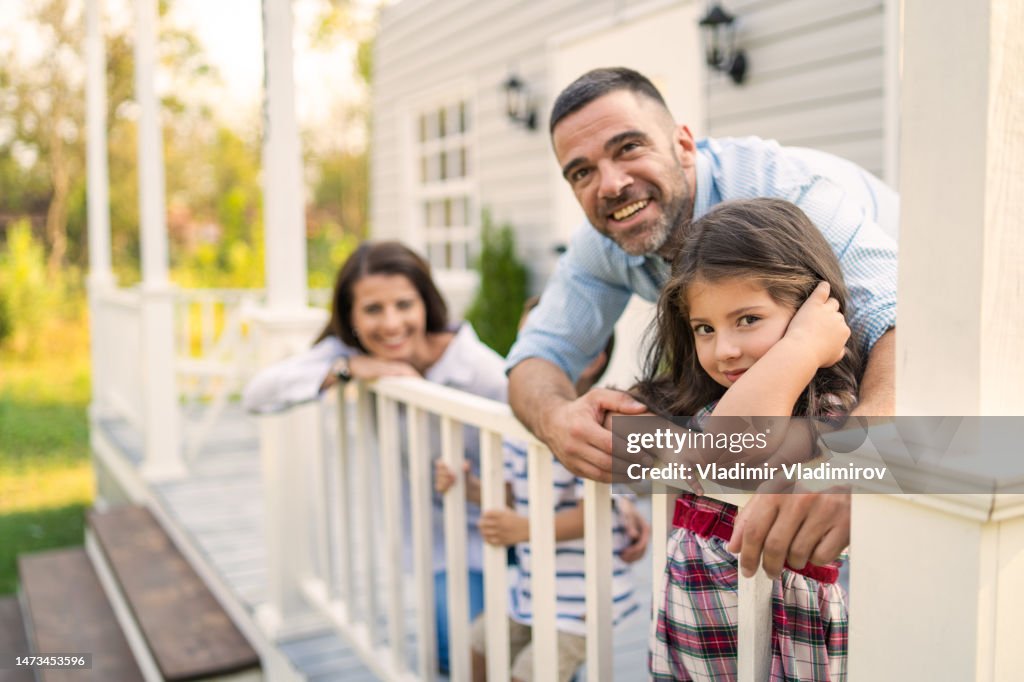 Two parents cuddling young daughter and baby son outdoors on the porch