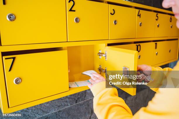 worried woman opening yellow mail box in hallway. etting huge electricity bills - crisis response unit stock-fotos und bilder