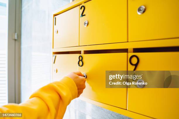 hand opening yellow mailbox with key in hallway of apartment building - boîte aux lettres photos et images de collection