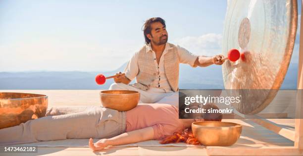 hombre tocando gong para terapia de sonido - gong fotografías e imágenes de stock